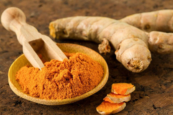 um tigela com cúrcuma em pó e no outro as raízes