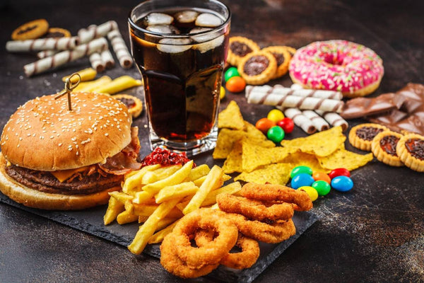 Copo com refrigerante, hambúrguer, batata frita e doces